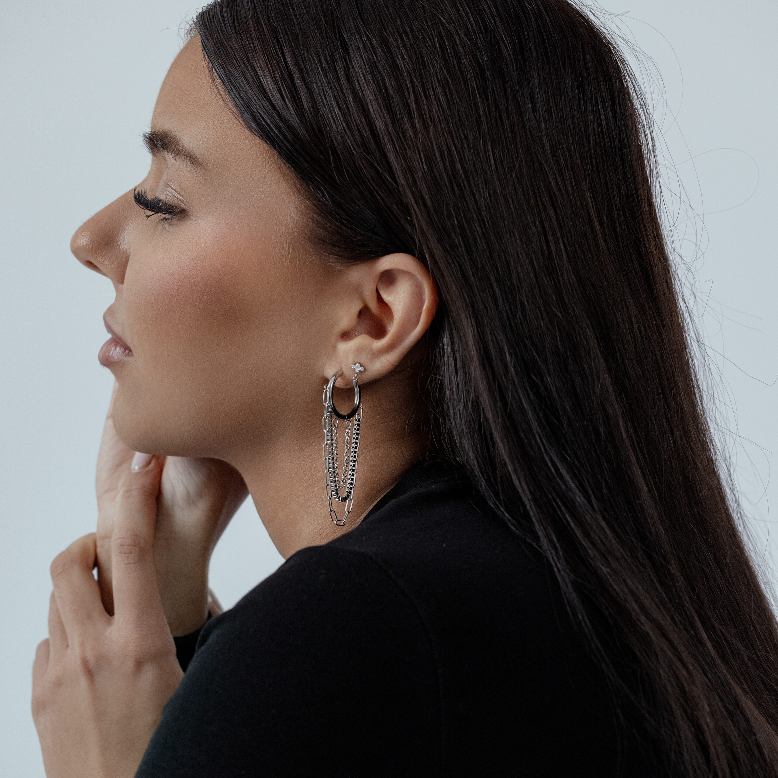 Donna con capelli neri indossa orecchini a cerchio multistrato in argento su sfondo chiaro