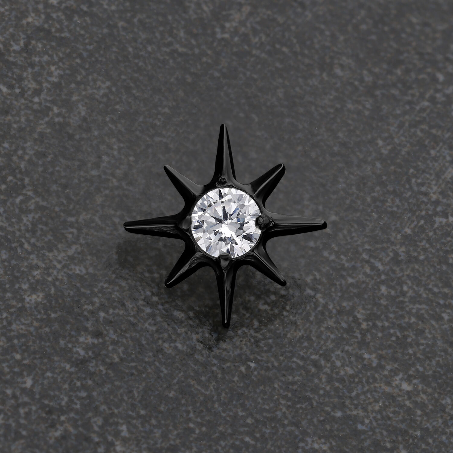 Perno a stella in metallo nero con cristallo chiaro su sfondo grigio