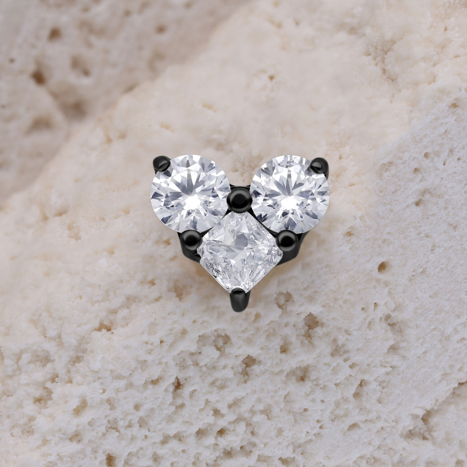 Accessorio in metallo nero con tre cristalli chiari su sfondo chiaro