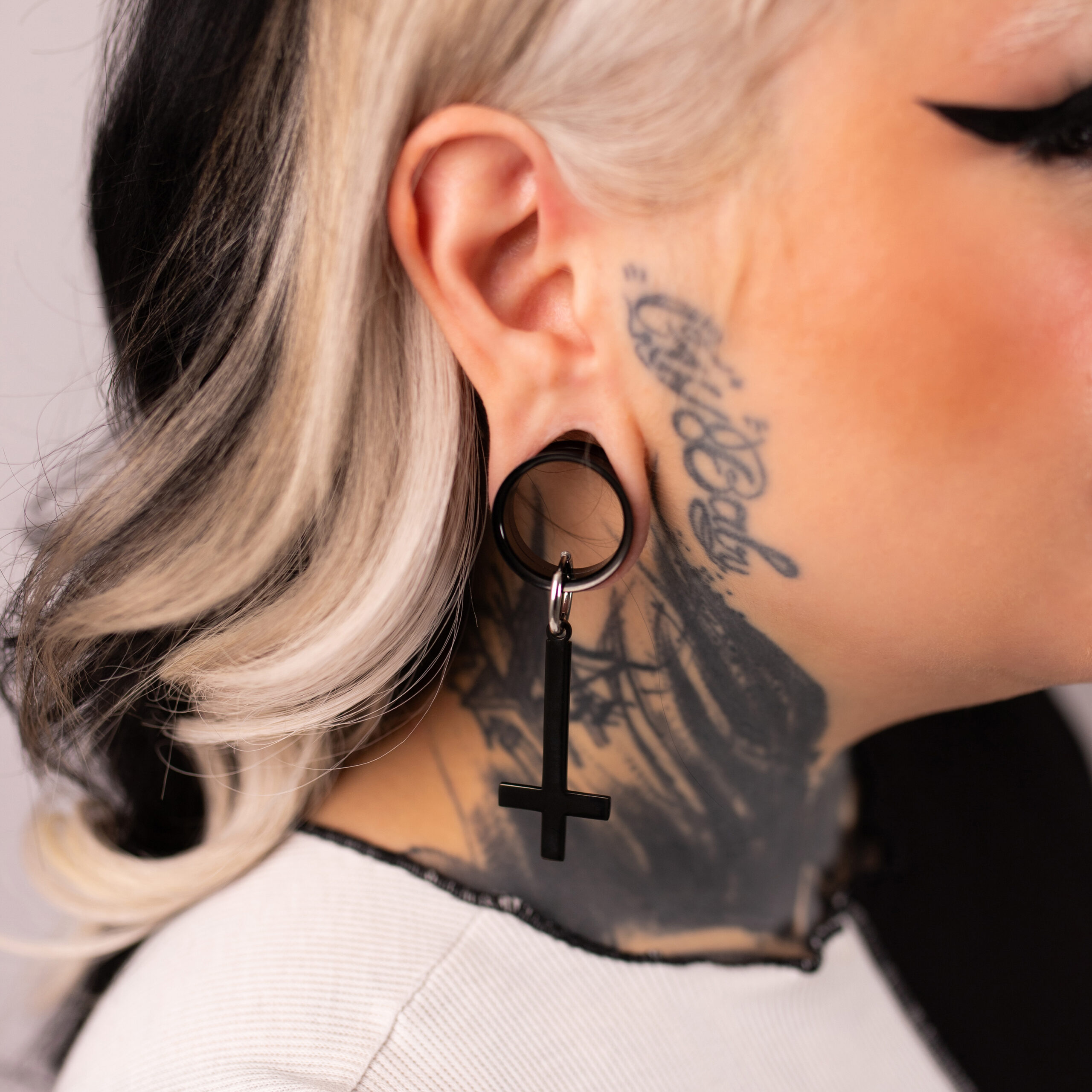 Verena Venus Cross Hoops in Nero Orecchini Cross Hoops neri in acciaio chirurgico 316L su un orecchio con tatuaggio