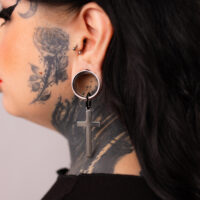 Verena Venus Cross Hoops in argento e nero Orecchini a croce in argento e nero su un orecchio tatuato