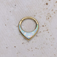Clicker septum dorato con opale sintetico su sfondo chiaro