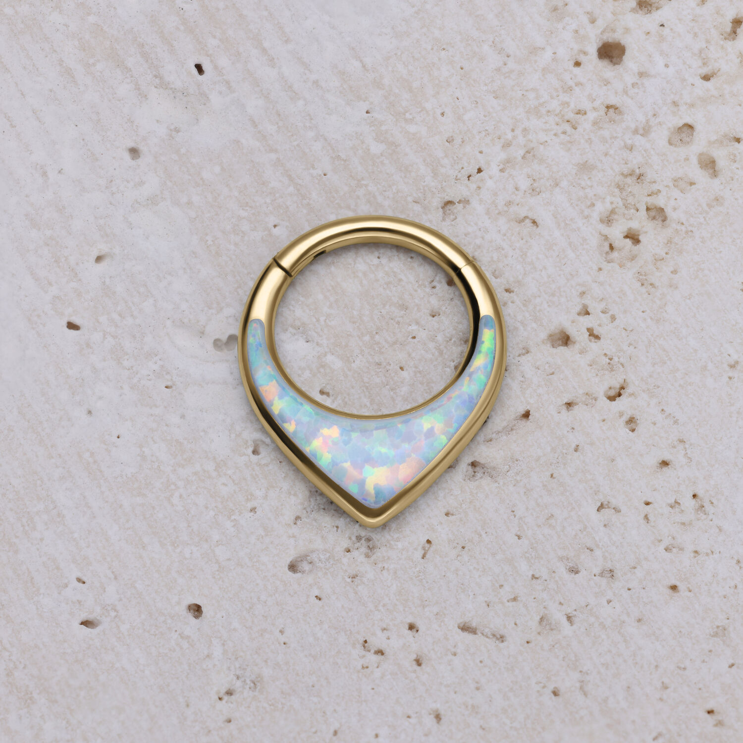Clicker septum dorato con opale sintetico su sfondo chiaro