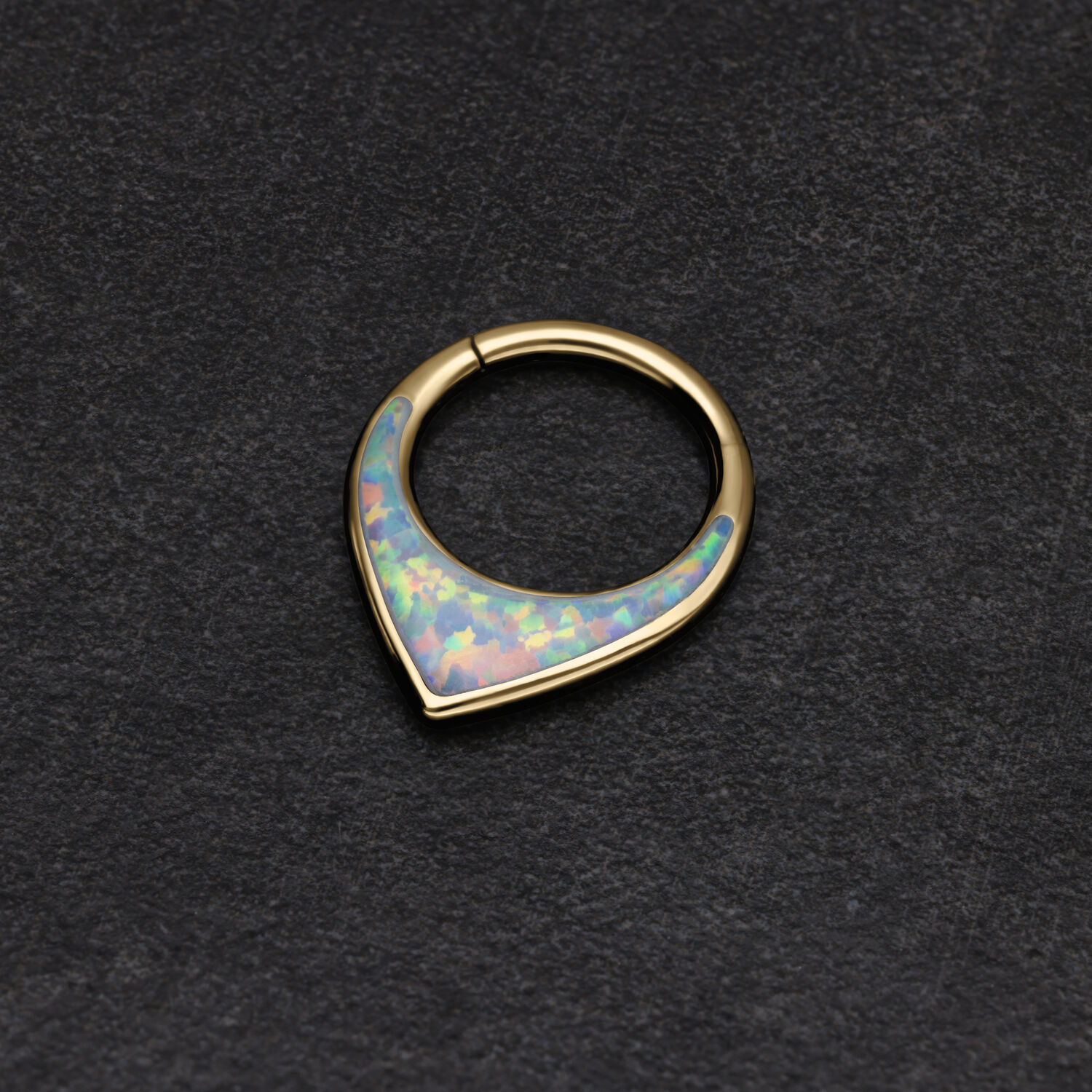 Anello per setto in oro con opale sintetico scintillante su sfondo scuro