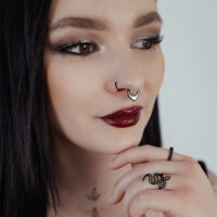 Donna con septum clicker nero e lucentezza opale su sfondo chiaro