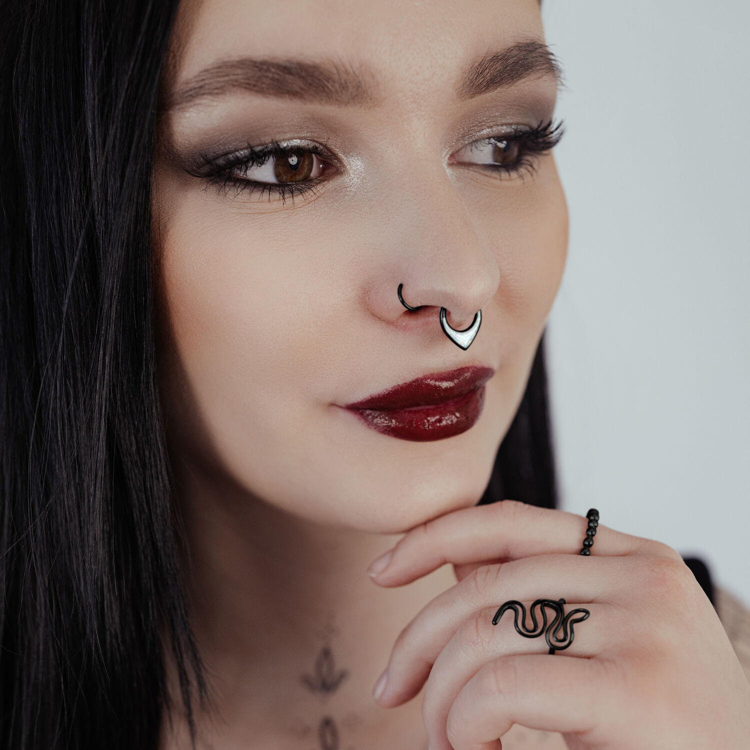 Donna con septum clicker nero e lucentezza opale su sfondo chiaro