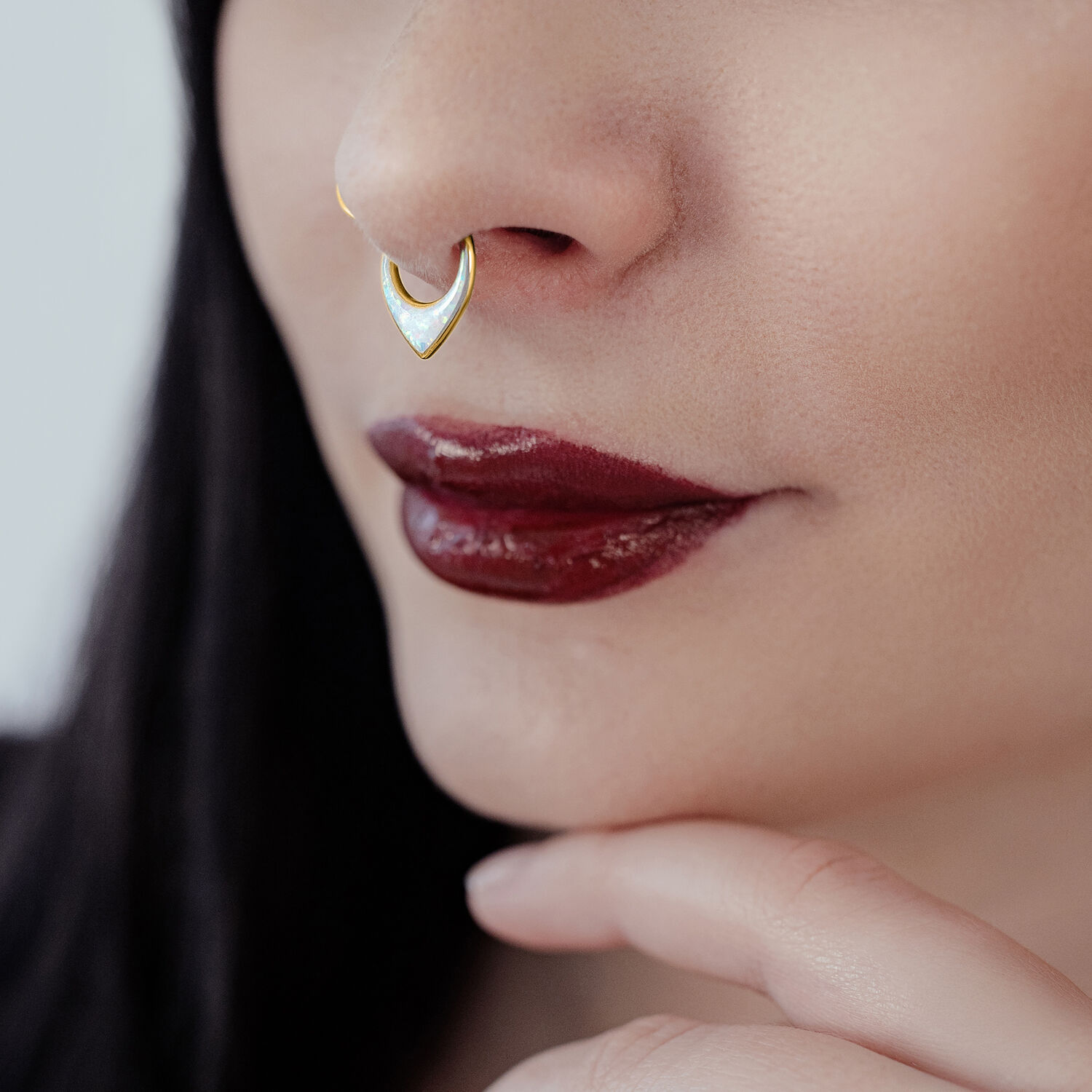 Donna con clicker per setto in oro di titanio e opale bianco su sfondo neutro
