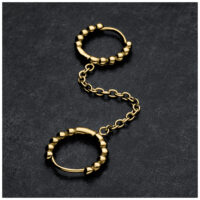 Doppelte Huggie-Ohrpiercings in Gold mit Kugeln und Kette auf dunklem Hintergrund