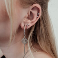 Primo piano di un orecchio con punta per piercing in argento e cristalli chiari