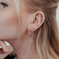 Primo piano di un orecchio con punta per piercing elegante e ciondolo di cristallo