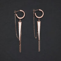Due orecchini in oro rosa con design a triangolo e catene su sfondo nero
