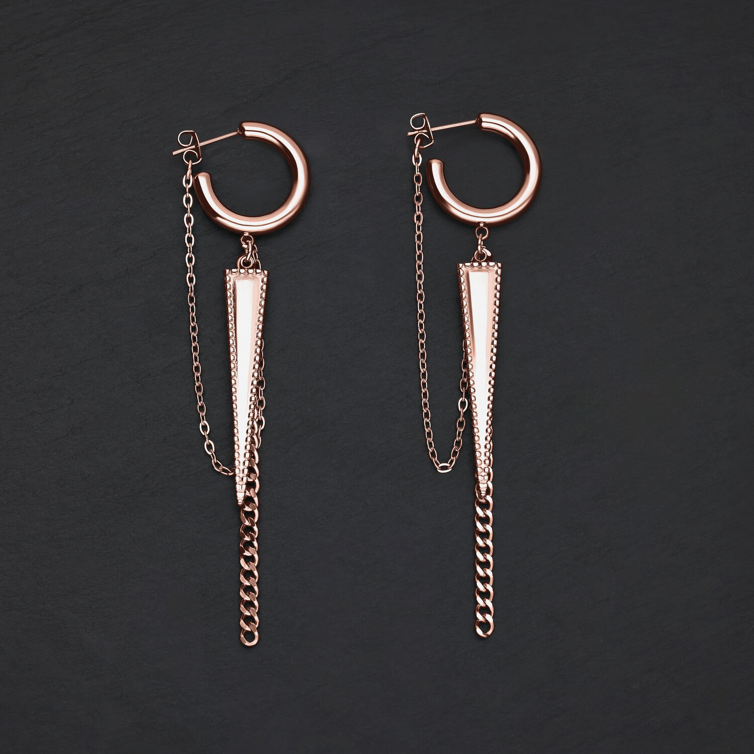 Due orecchini in oro rosa con design a triangolo e catene su sfondo nero