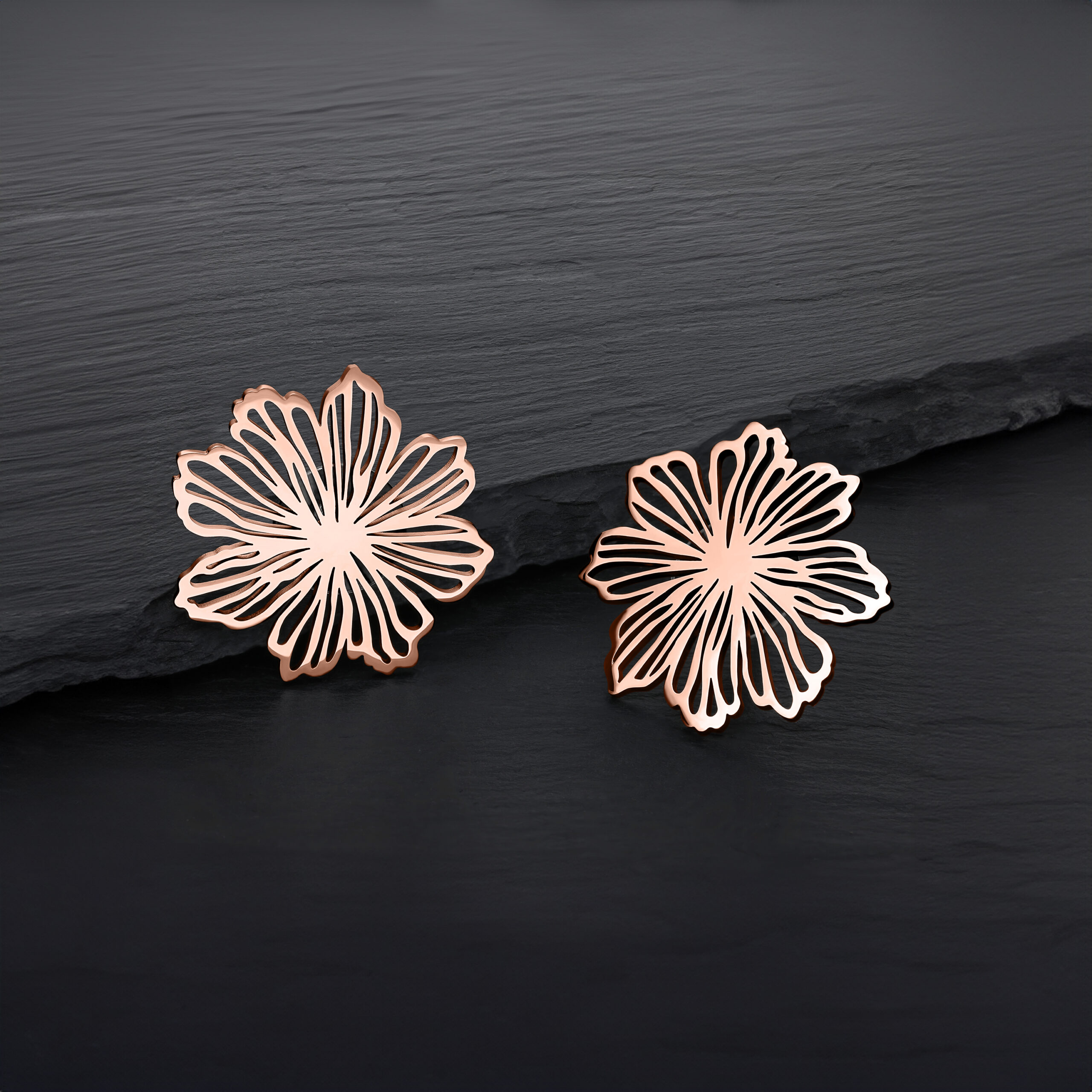 Due orecchini a fiore in oro rosa su sfondo nero