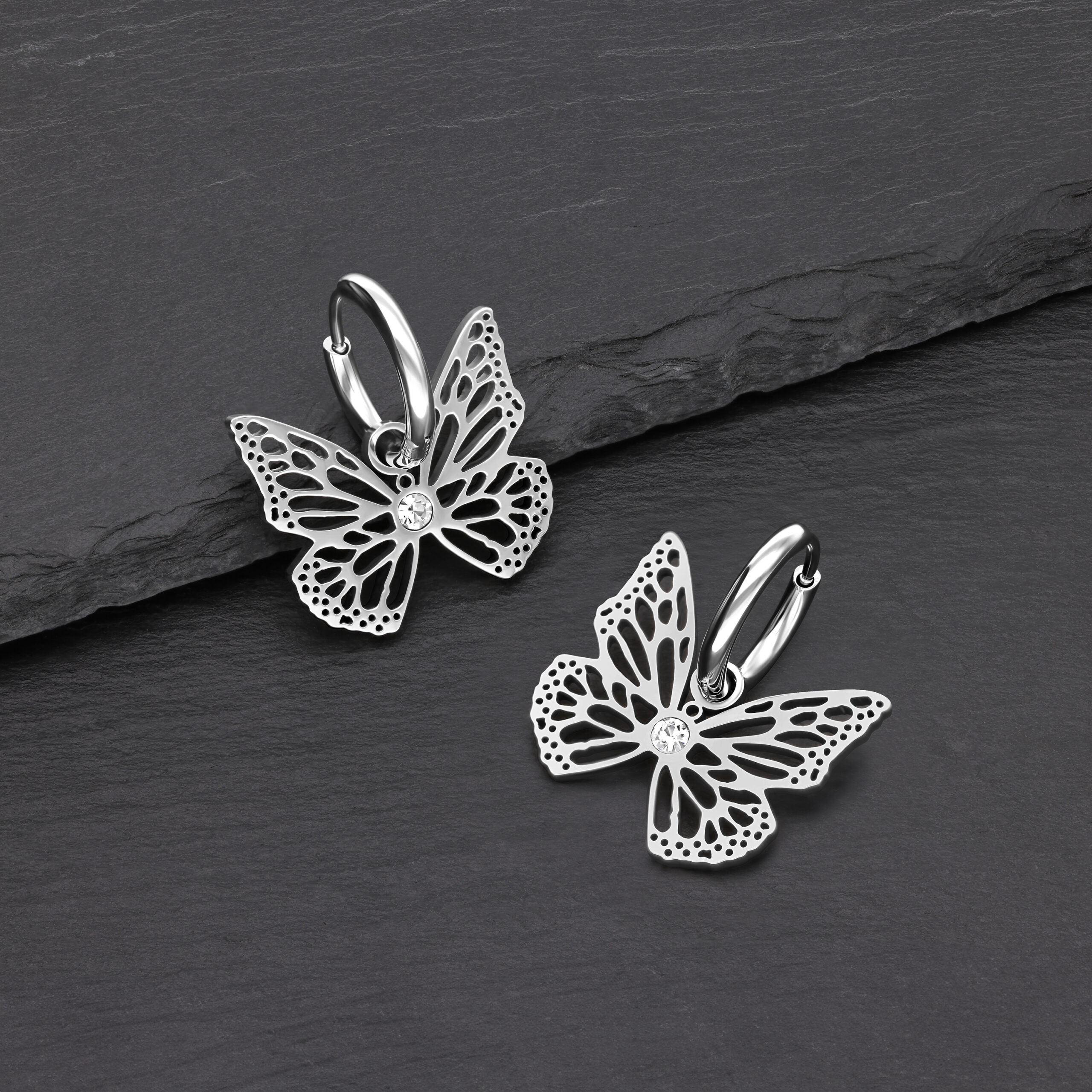 Due orecchini a farfalla in argento su sfondo nero in acciaio inox