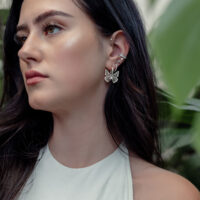 Donna con orecchini Butterfly in argento, all'aperto, con piante sullo sfondo