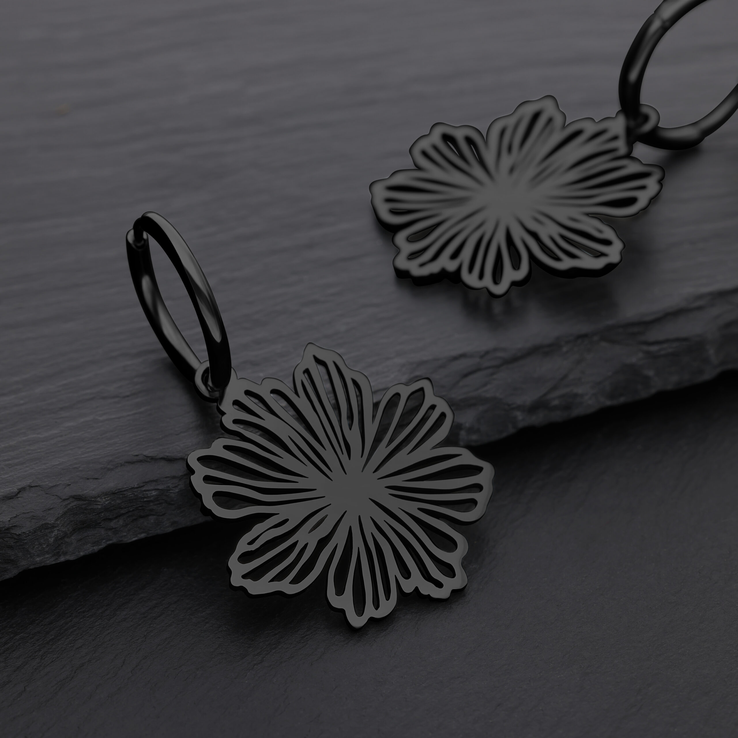 Orecchini a fiori neri in acciaio chirurgico su sfondo grigio