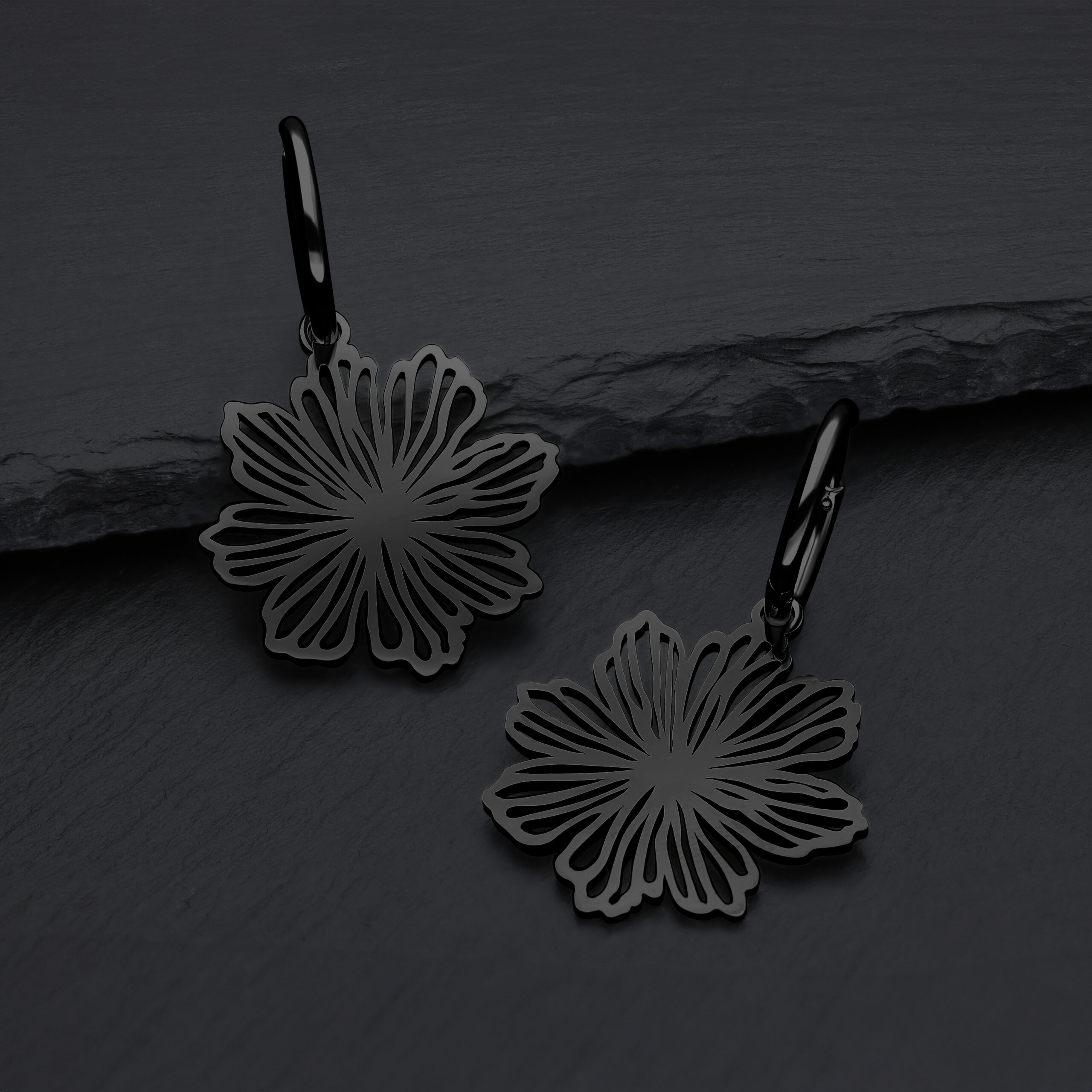 Orecchini neri a forma di fiore in acciaio chirurgico su sfondo grigio