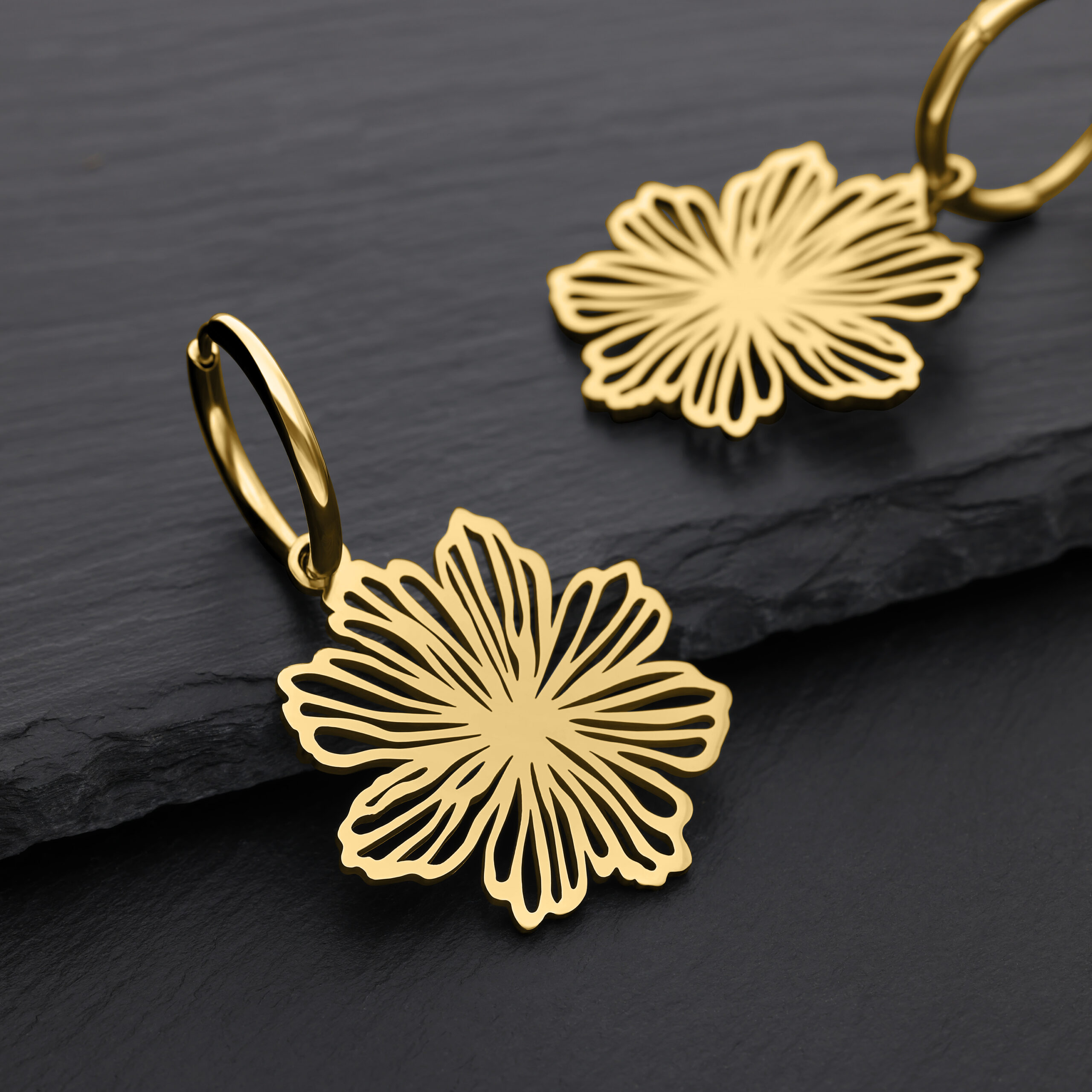 Orecchini Fine Flower dorati in acciaio chirurgico Due orecchini dorati a forma di fiore su sfondo nero