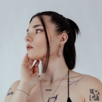 Donna con orecchini a cerchio neri e argento, fotografata di lato