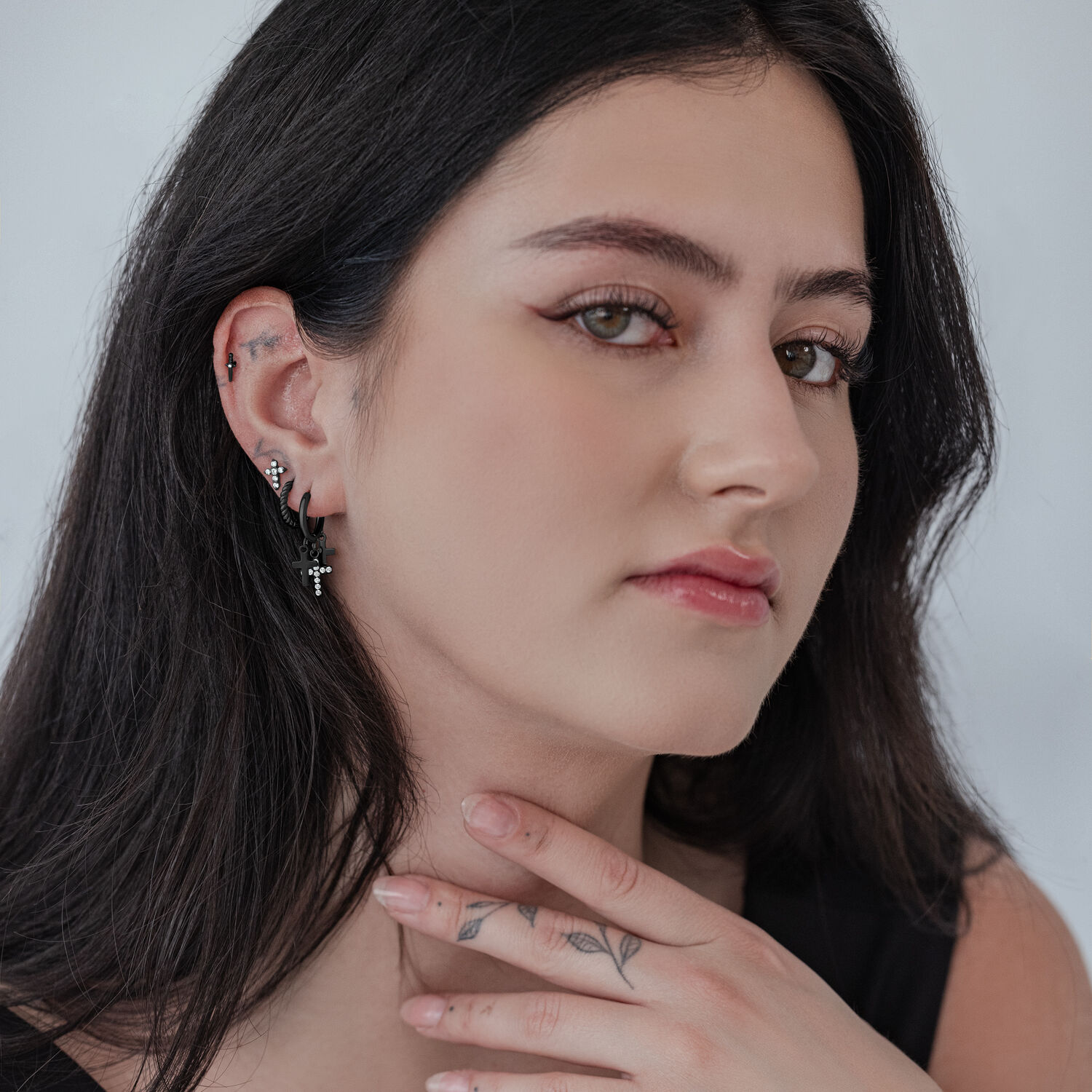 Donna con orecchini pendenti a croce neri su sfondo chiaro