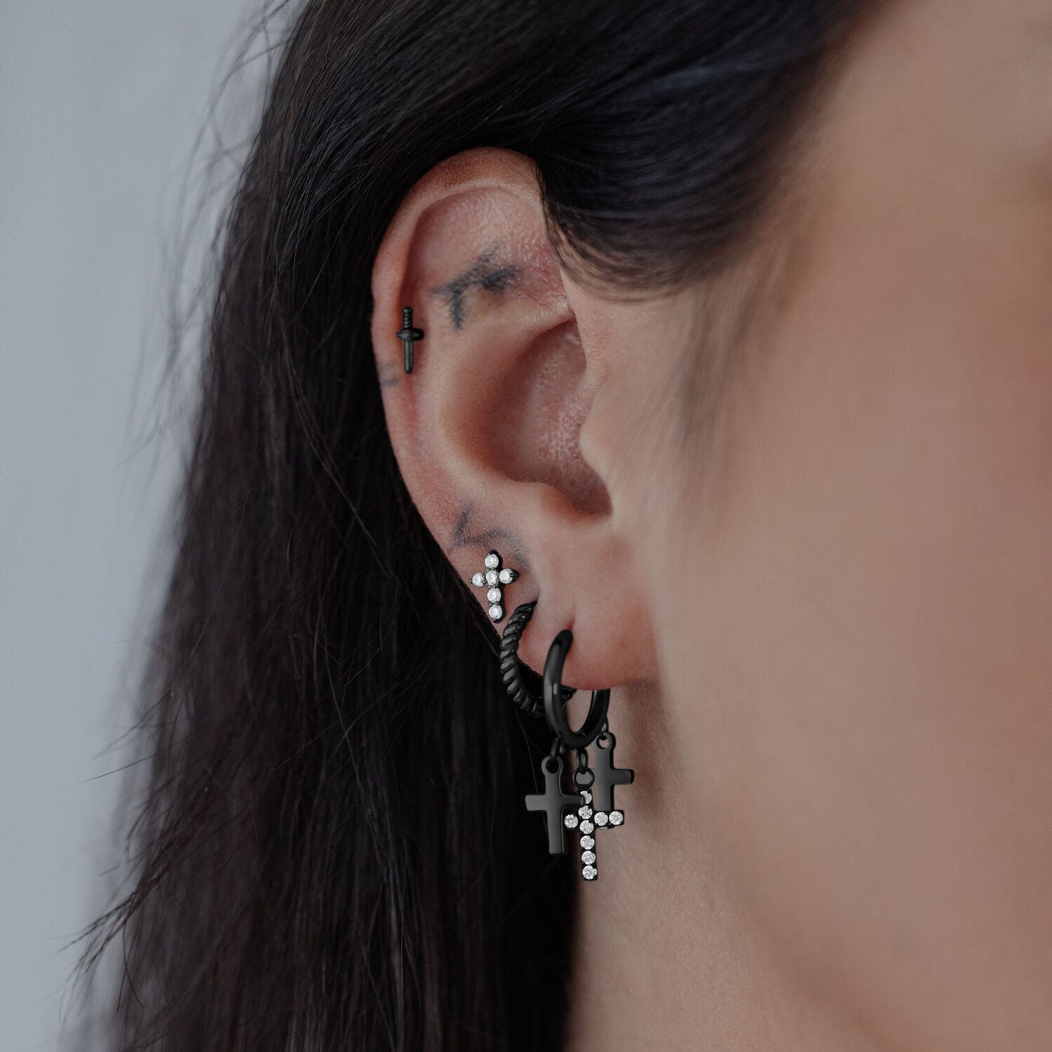 Orecchini a croce neri su un orecchio, acciaio chirurgico lucido