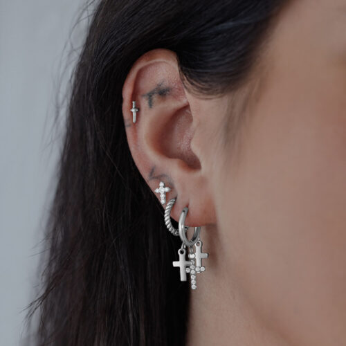 Orecchini a cerchio in argento con pendenti a croce su un orecchio