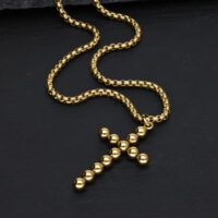 Collana Croce Bubble Dorata in Acciaio Chirurgico Collana croce dorata con sfere su sfondo nero