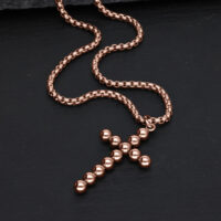 Collana in oro rosa con ciondolo a croce di sfere su sfondo nero