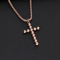 Collana a croce in oro rosa in acciaio chirurgico su sfondo scuro