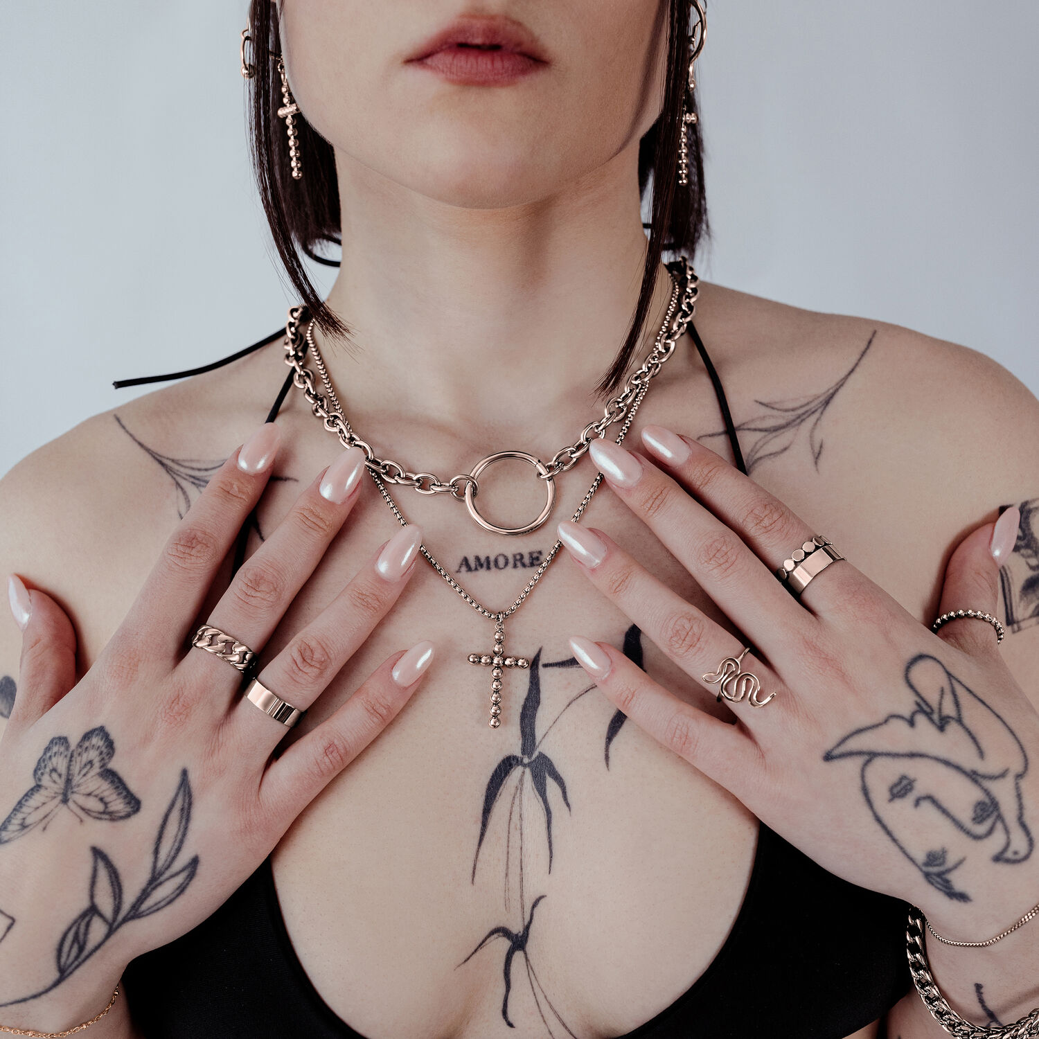 Donna con Collana Bubble Cross in Oro Rosa e tatuaggi su sfondo neutro