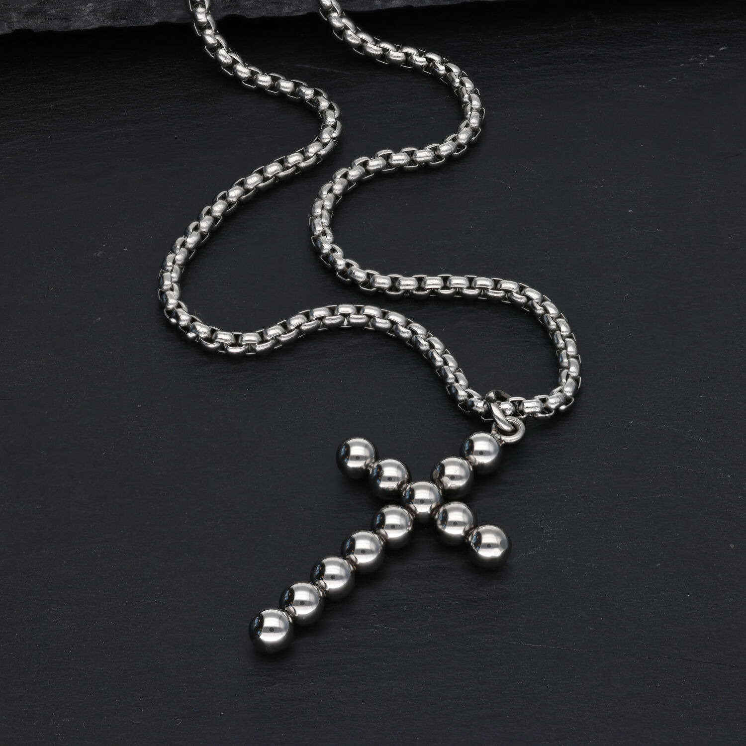Collana a croce argento con design a sfere su sfondo nero