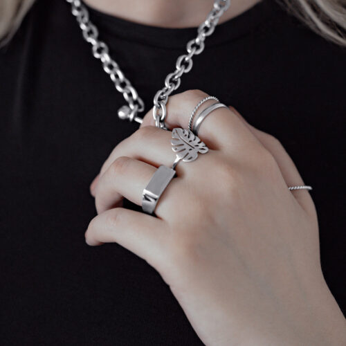 Anello d'argento con foglia di Monstera su una mano, indossato con altri anelli