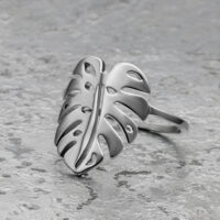 Anello foglia di Monstera in argento in acciaio chirurgico su sfondo grigio