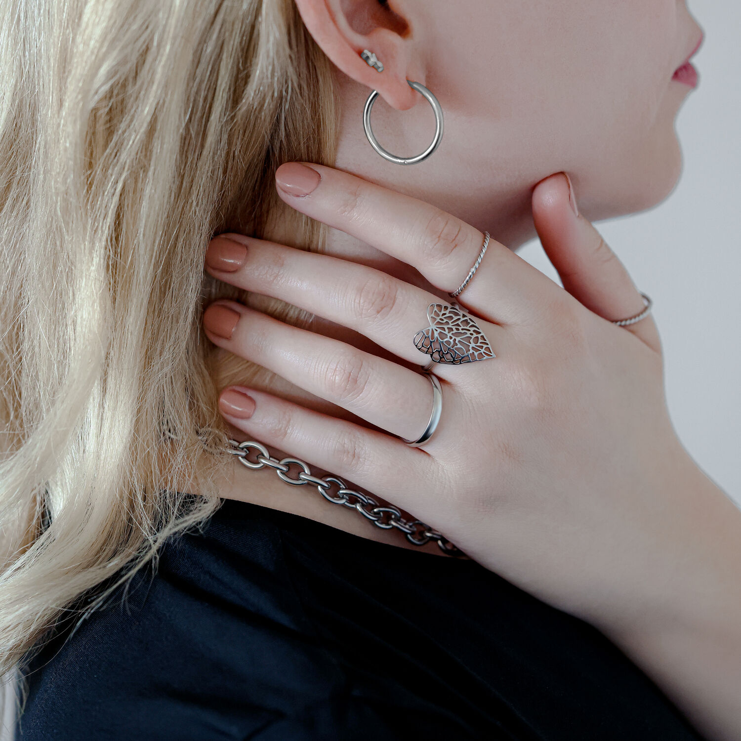 Anello Lovely Leaf Argento sulla mano di una donna che tiene una collana