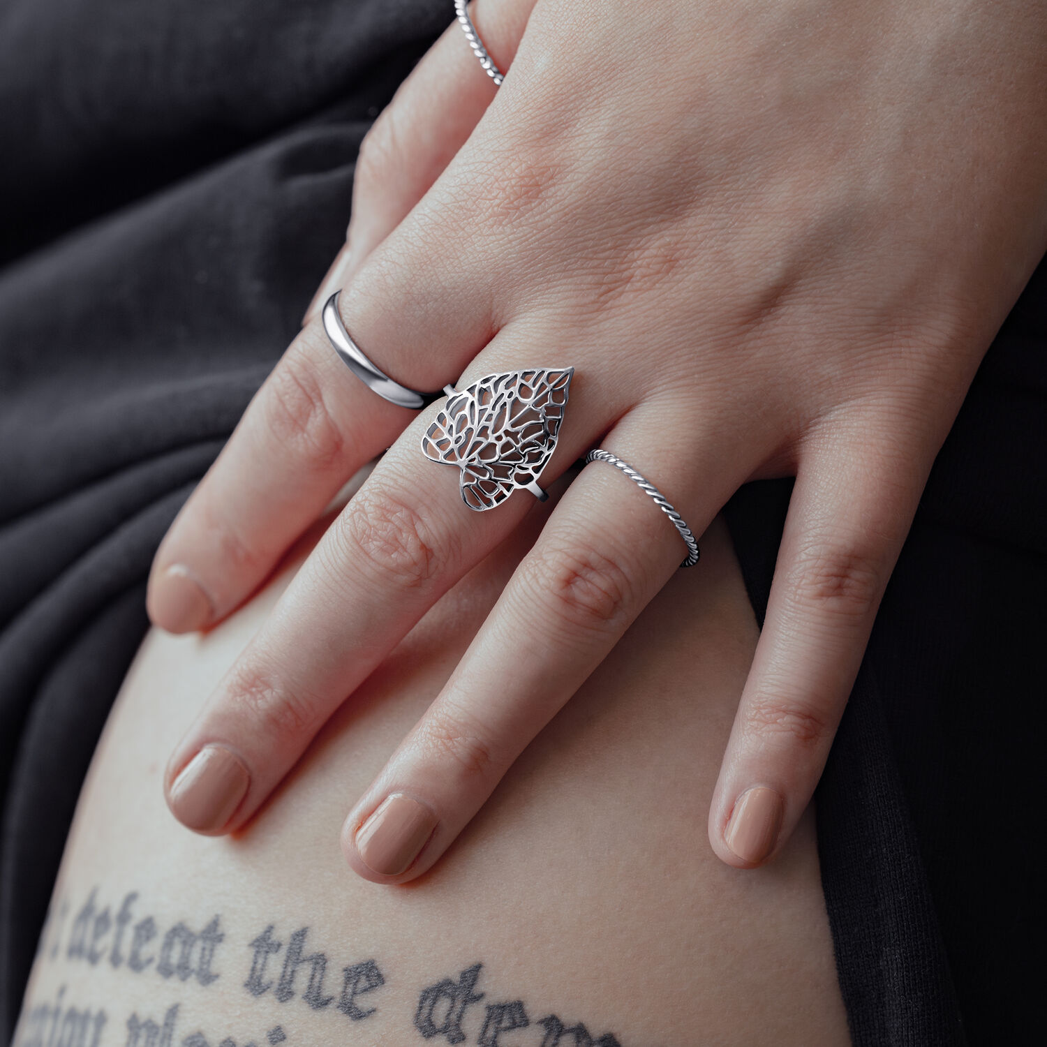 Anello in argento con design a foglia su mano femminile su sfondo nero