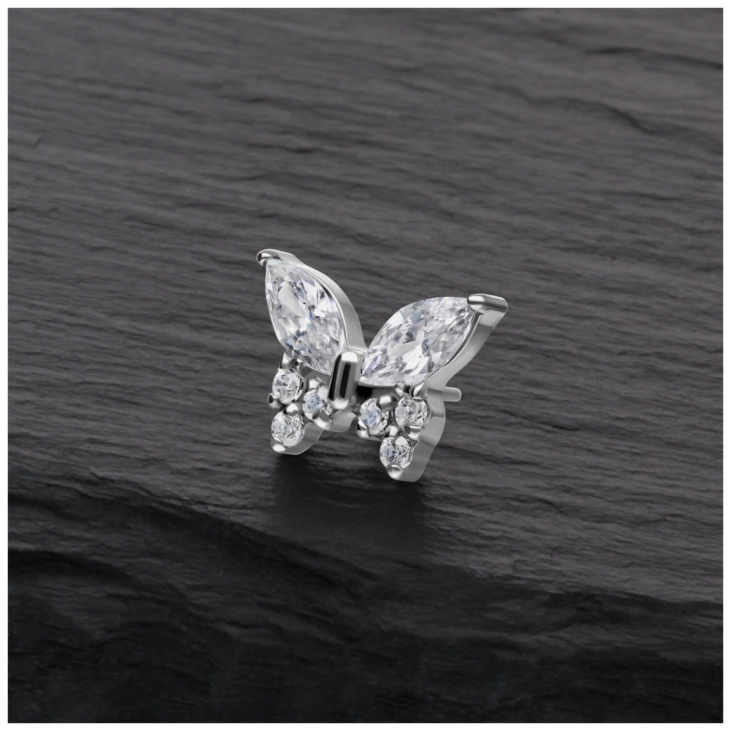 Accessorio piercing a farfalla color argento con cristalli chiari su sfondo scuro