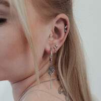 Primo piano di un orecchio con diversi piercing, incluso un grande inserto a stella di cristallo Push Fit argentato.