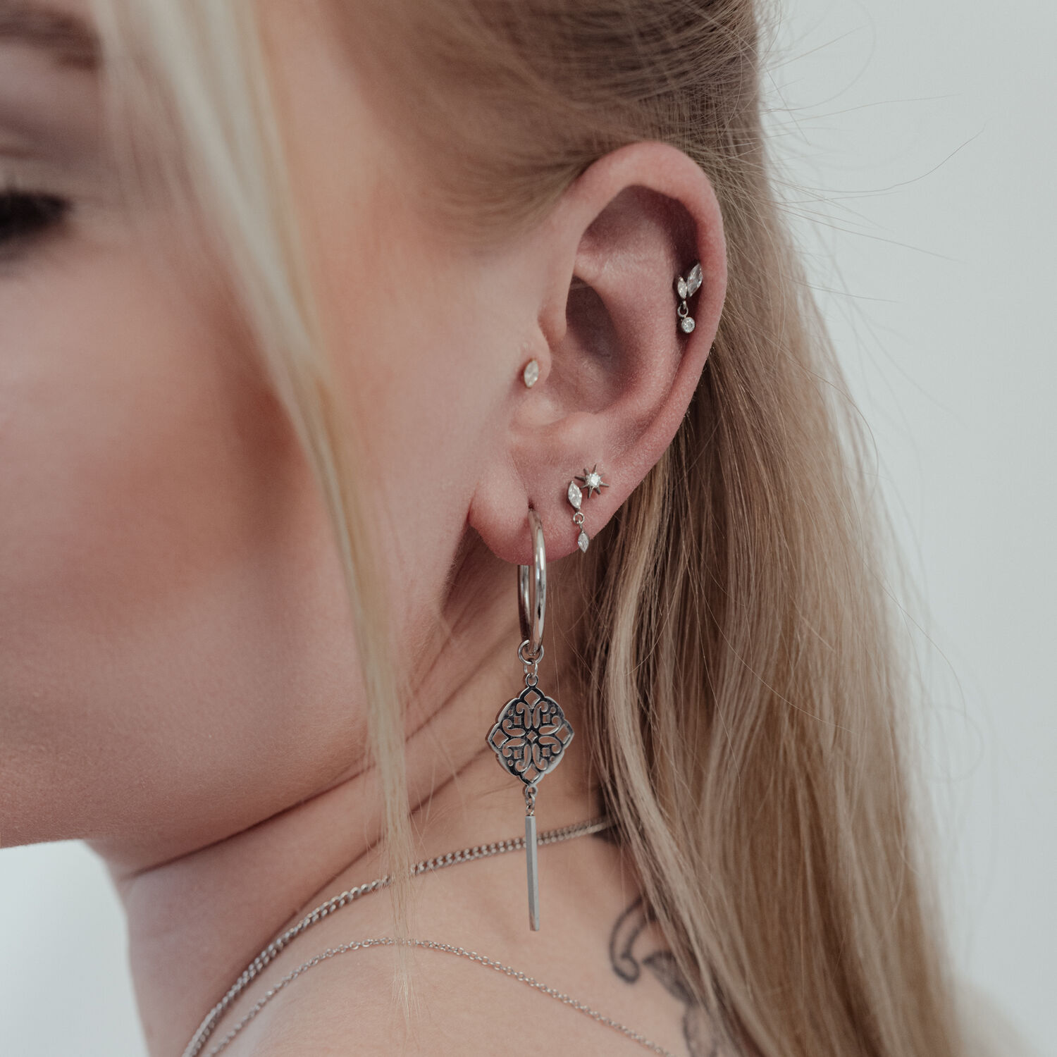 Primo piano di un orecchio con diversi piercing, incluso un grande inserto a stella di cristallo Push Fit argentato.