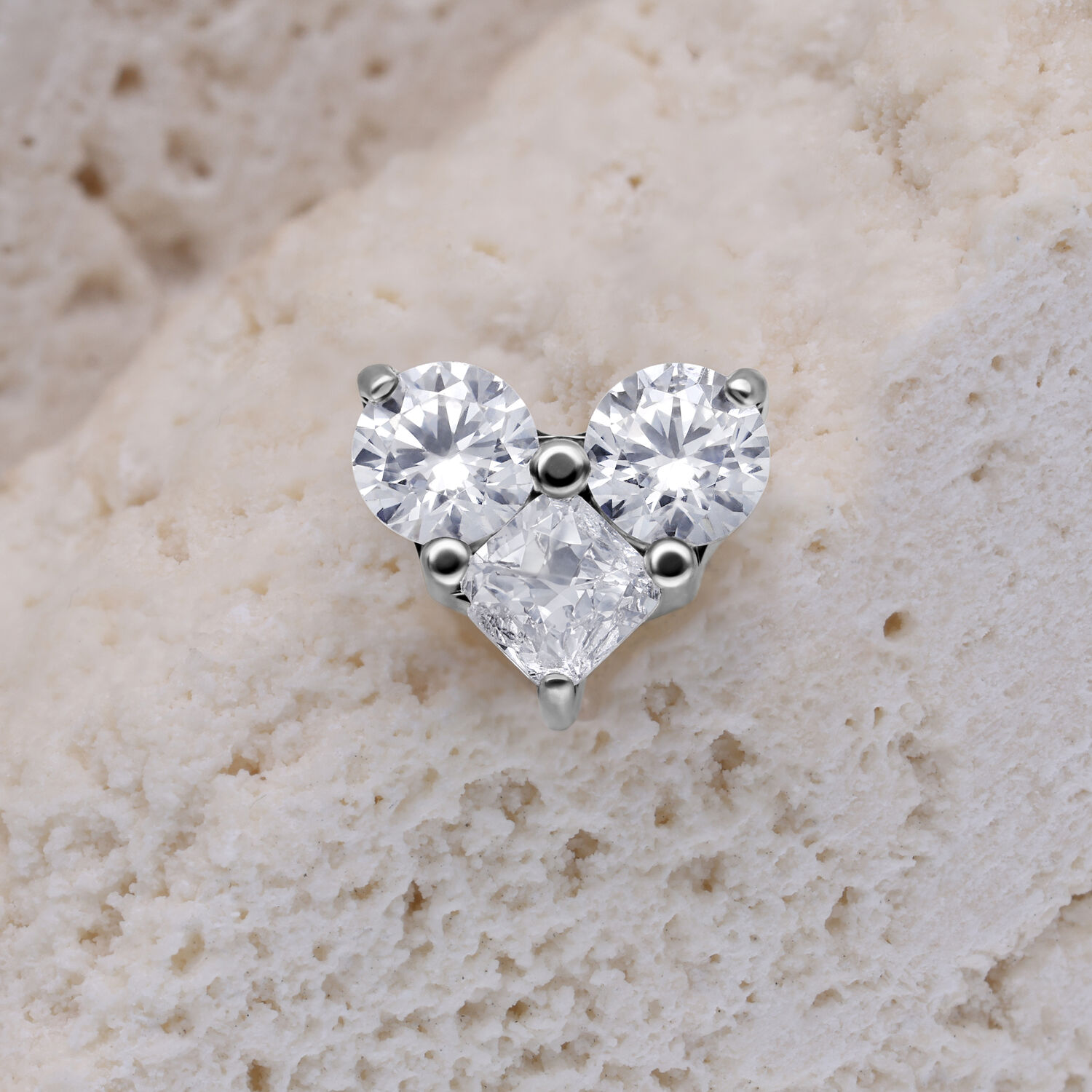 Cuore in argento con cristalli chiari su sfondo beige