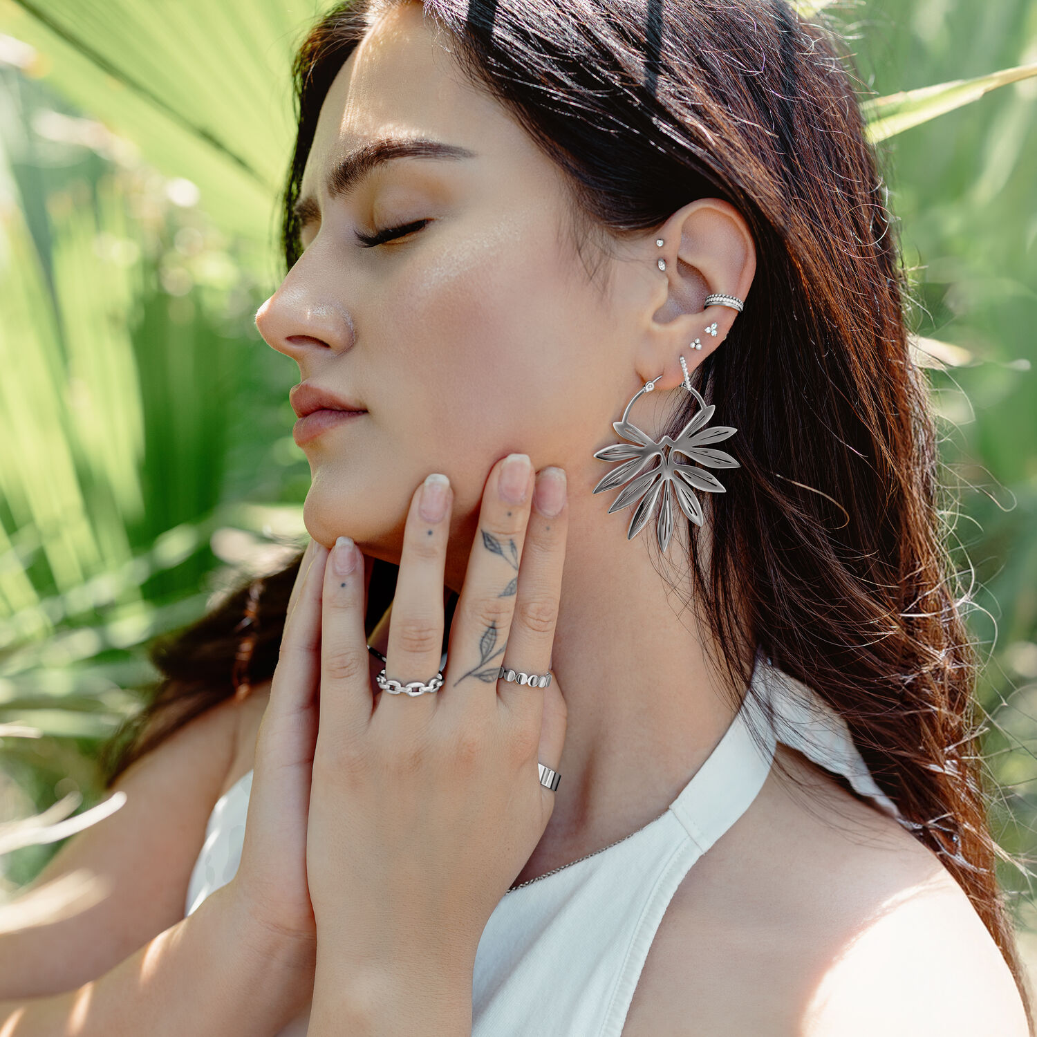 Donna con eleganti orecchini di bambù in nero e oro su sfondo verde