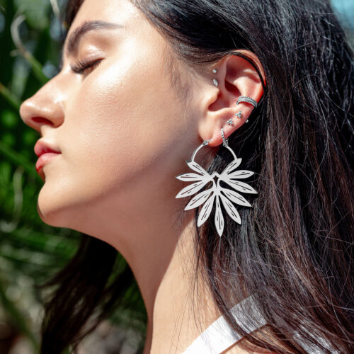 Primo piano di una donna con orecchini in bambù d'argento alla luce del sole