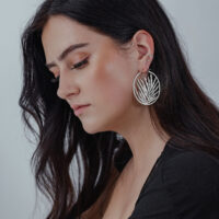 Orecchini Noble Leaf Hoops in argento su donna con capelli lunghi e scuri