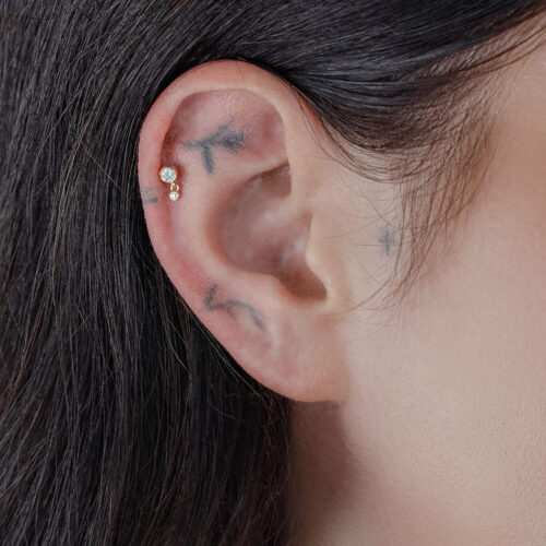 Attacco d'oro con due cristalli indossato sull'orecchio, primo piano