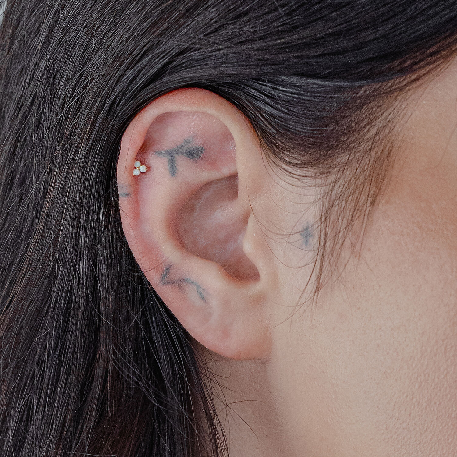 Accessorio in oro con opale sintetico in un piercing all'orecchio.