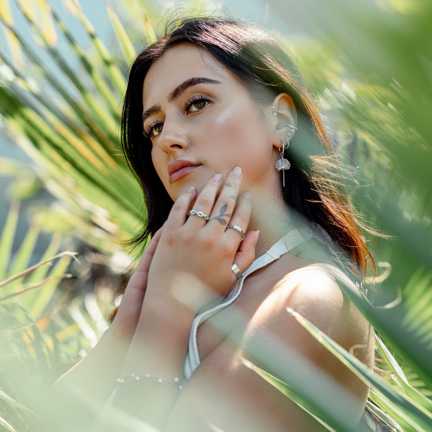 Donna con orecchini Little Petticoat Hoops davanti a foglie verdi