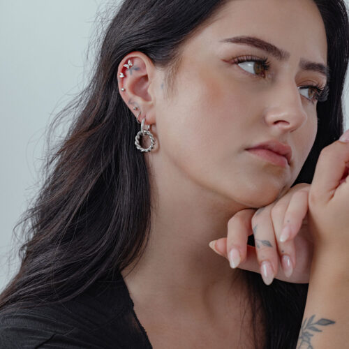 Donna con capelli lunghi indossa Twisted Circle Hoops in argento, profilo laterale