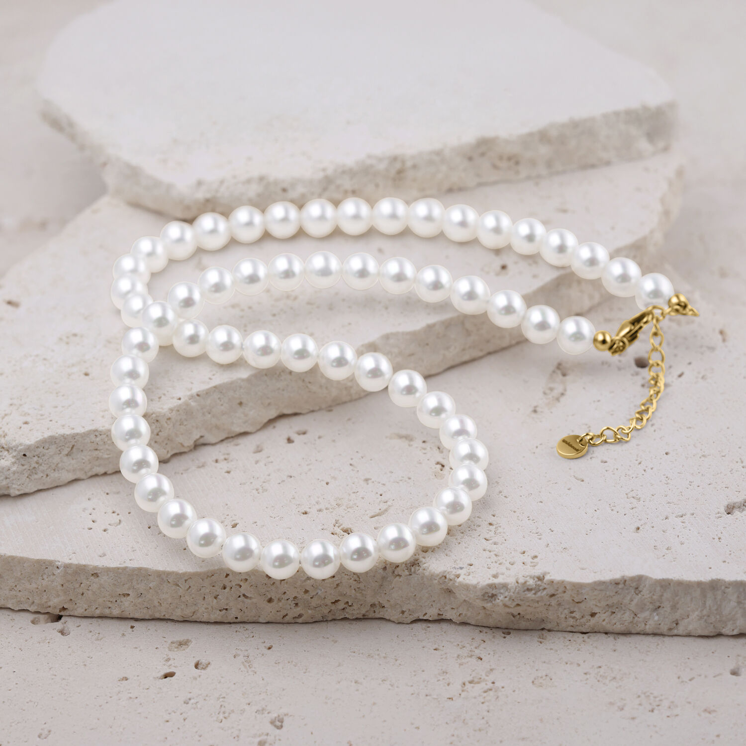 Grande collana di perle argento-oro con chiusura dorata Grande collana di perle sintetiche in argento con chiusura dorata su sfondo chiaro
