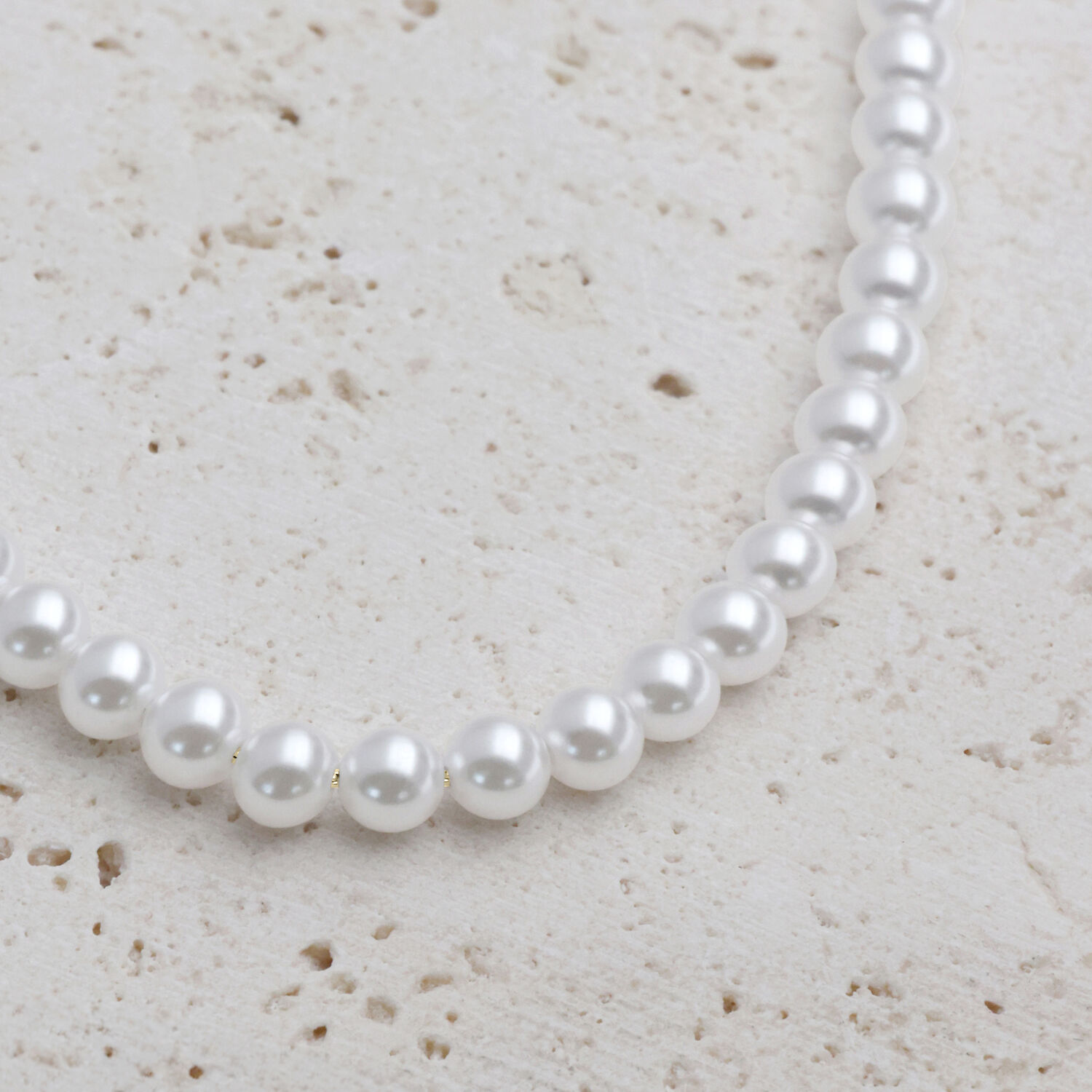 Grande collana di perle dettaglio argento-oro Grande collana di perle sintetiche con elementi metallici dorati su sfondo chiaro
