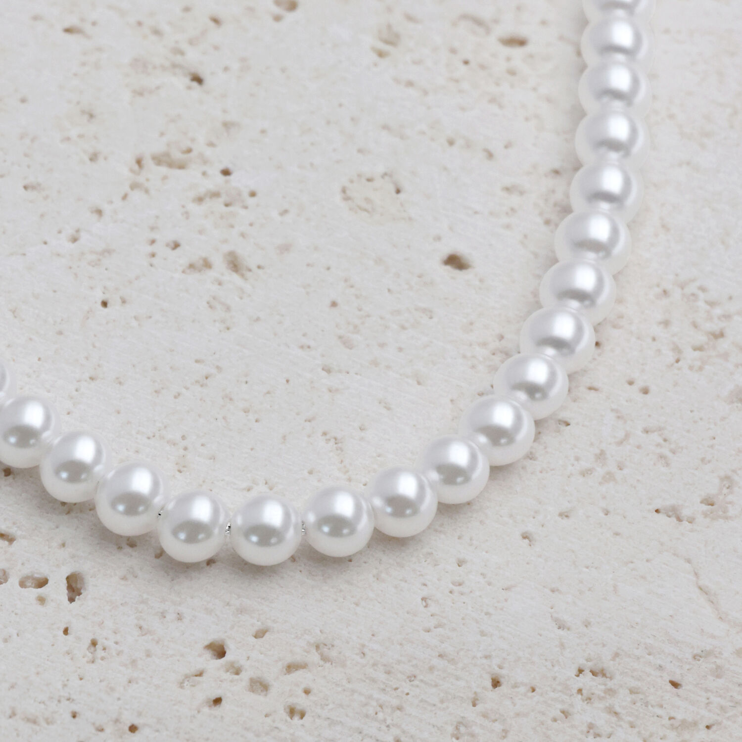 Collana di perle sintetiche argento su sfondo di pietra chiara