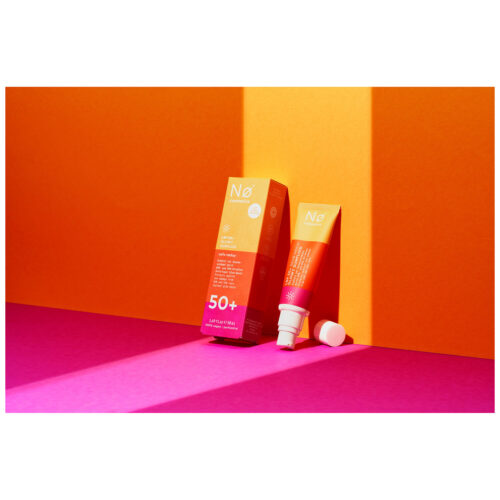 No Cosmetics Glowy Sunfluid in tubo davanti a sfondo arancione e rosa